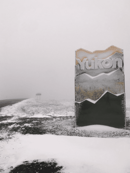 <i>23 juni 2025</i>
Terwijl ik deze MetGroetJess in de steigers zet, rijden de Verkering en ik rond door de Yukon en een stukkie door Alaska, over de Top of the World Highway om precies te zijn.
Het plan was om in mijn groene polkadot-bikini een dip te doen in de Arctic Ocean. Ik had zelfs bijpassende teenslippers gekocht bij de Dollarama in Whitehorse. Zodat je makkelijker over de oceaankiezels kan lopen terwijl je je verbijt aan de waterkou die je de adem beneemt, aldus deze ervaringsdeskundige. Een goede voorbereiding is immers het halve werk.
Maar zonder drama geen verhaal: we hebben het niet gered om helemaal naar Tuktoyaktuk te geraken. Het drama zat ‘m in de ferries. Dat leg ik even uit:
Tuktoyaktuk ligt aan het einde van de meest noordelijke weg van dat onbevattelijk grote Canada. Eerst rij je een stuk over de befaamdberuchte Dempster Highway (start ligt bij Dawson City, ongeveer) tot aan Inuvik. Om helemaal naar Tuk te kunnen geraken heb je 2 ferry overtochten nodig. De eerste is over de Peel River, bij Fort McPherson. De tweede over de MacKenzie River en dan kun je door naar Inuvik. En van Inuvik naar Tuk ligt een goed begaanbare asfaltweg. Blijkbaar. Want die heb ik dus niet kunnen aanschouwen. Het zat zo:
Ik denk dat we een week te vroeg waren. Als het voorjaar warmer was geweest dan had het zomaar wel gelukt, dan was het ijs allang gesmolten. En dan had de ferrie operabel kunnen zijn. Maar het is een heel koud voorjaar geweest. Nu lagen er nog teveel ijsschotsen in de rivier. Plus boomstammen en ander spul wat niet in de rivier thuishoort maar wel in de weg ligt voor de ferry. Op Tombstone Campground, aan het begin van de Dempster, gonsde het ook al van andere avonturiers. Gaat de ferry wel? Of over een paar dagen pas? Met 4WD uitgeruste Mercedesbussies, reservebanden met spanbanden op het dak vastgebonden, extra benzine tanken. Want The Dempster heeft maar één benzinestation en dat is op Eagle Plains. En het is een gravelroad met veel scherpe steentjes. En dan heb ik het nog niet eens over de beren die plots de berm uit komen. Motorrijders die ál hun extra thermoleggings aantrekken op de parking van Tombstone Interpretive Centre. Voor de ruige trip naar het Hoge Noorden. Nou koud was het! We stonden in minus 4 graden ergens langs de kant van de weg te kamperen in een sneeuwstorm. Zonder bereik, zonder ook maar enig teken van leven in de verste verte omtrek. Larger than life!
De Yukon: Geen Tim Hortons, geen McDonalds, geen Canadian Tyre, geen Save-on-Foods. Nou vooruit, alleen in ‘de grote stad Whitehorse’ en dat schrijf ik expres tussen aanhalingstekens. Want feitelijk is het een groot dorp. In de overige stadjes/dorpjes waar je langs rijdt, tref je één benzinepomp, waar je ook je gastank voor de camper kan bij laten vullen. Met één General Store waar je yoghurt kan kopen. En als het meezit een oranje paprika en een doosje alfalfa. En een ‘kleine doos’ eieren waar er minstens tien inzitten. Ook dat staat expres tussen aanhalingstekens.
Dit is tevens een ode aan de Verkering. Een helehalve koffer vol met draadjes, camera’s, Leathermannen en andere handige dingen gaan mee de oceaan over. Filmpjes, reels en foto’s, hij knoopt het allemaal aan elkaar. Om uiteindelijk het teveel-stof-in-de-scharnieren-probleem op te lossen met een paar emmers water. Stof? Probleem? Ja stof kan voor een hoop problemen zorgen. Zoals dus scharnieren van een camperluikje. Dan zit je je op de Dempster druk te maken over lekke banden en over het al dan niet bereiken van Tuk of dat de ferries aldanniet varen maar dan gaat er een luik ineens niet meer dicht. Tsja, dan kun je óók niet meer verder rijden.
Wat moet je zonder handige en gezellige Verkering in dit woeste landschap?
Yukon is larger than life.
De Verkering is my travelbuddy for life.